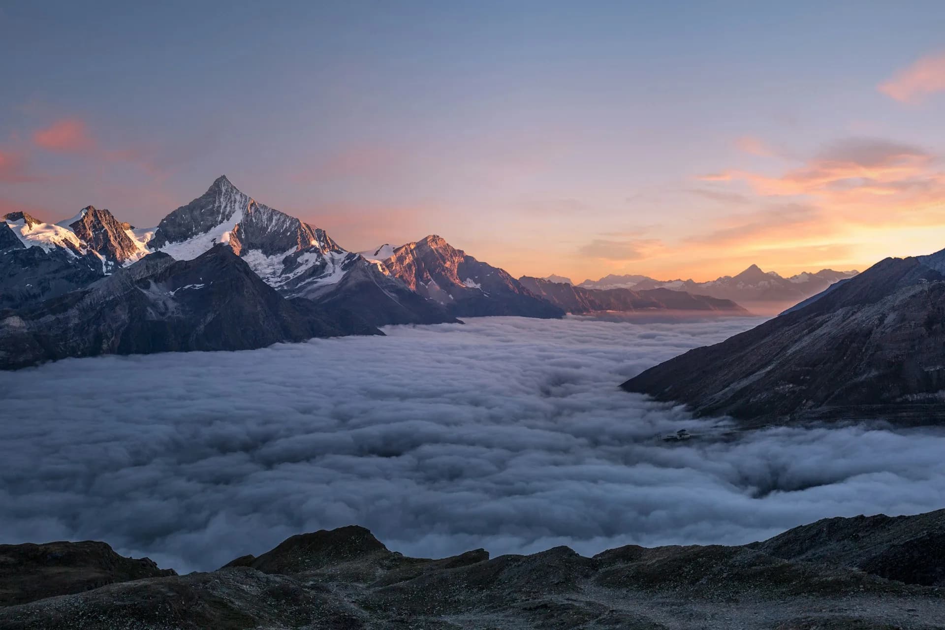 Montagnes au-dessus d'une mer de nuages, ciel au lever ou coucher du soleil
